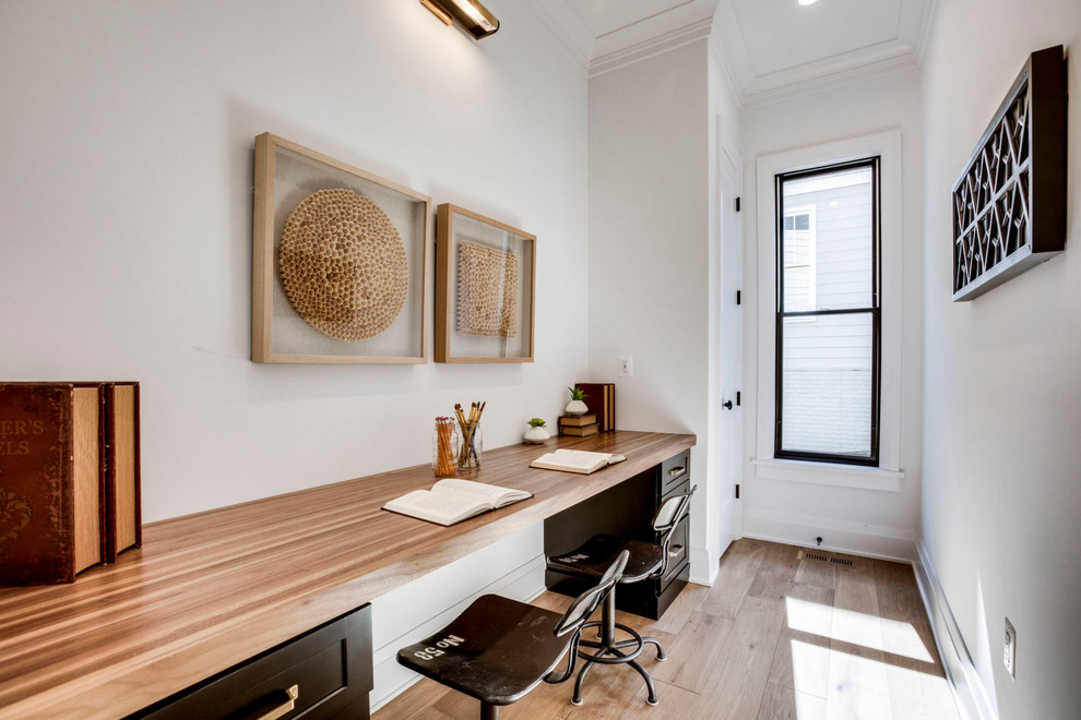 Foto de despacho clásico renovado sin chimenea con paredes blancas, suelo de madera clara y escritorio empotrado