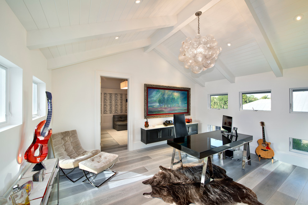 Diseño de despacho actual con paredes blancas, escritorio independiente, suelo de madera en tonos medios y suelo beige