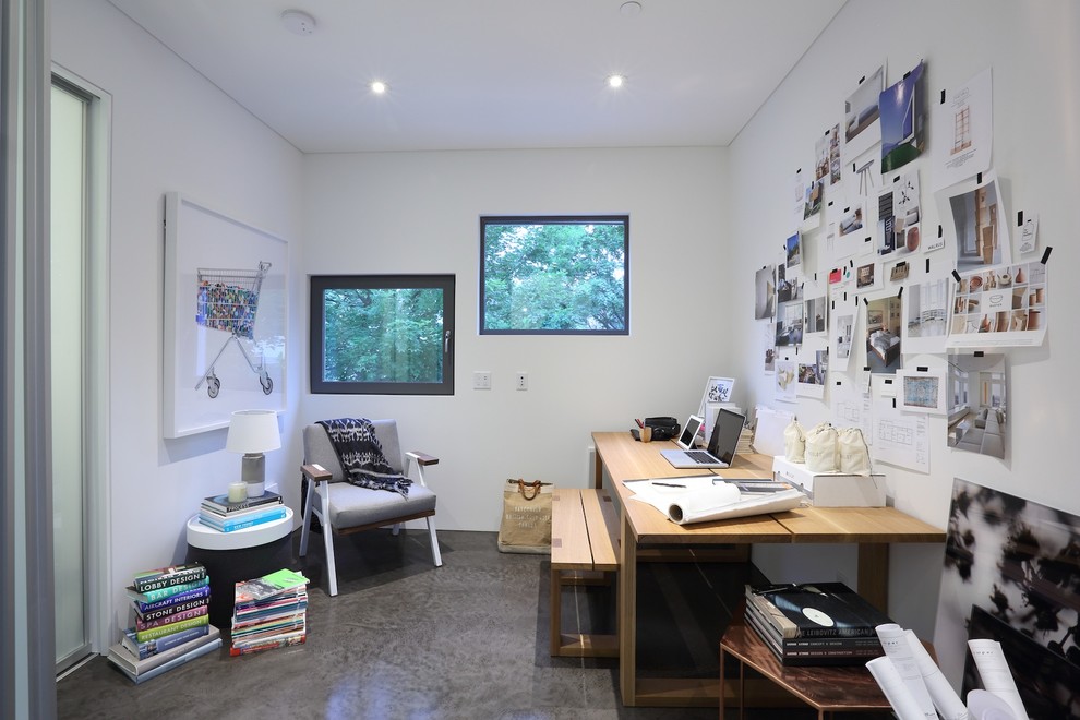 Modern inredning av ett litet hemmastudio, med vita väggar, betonggolv och ett fristående skrivbord