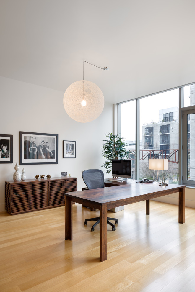 Modelo de despacho actual con paredes blancas, suelo de madera clara y escritorio independiente