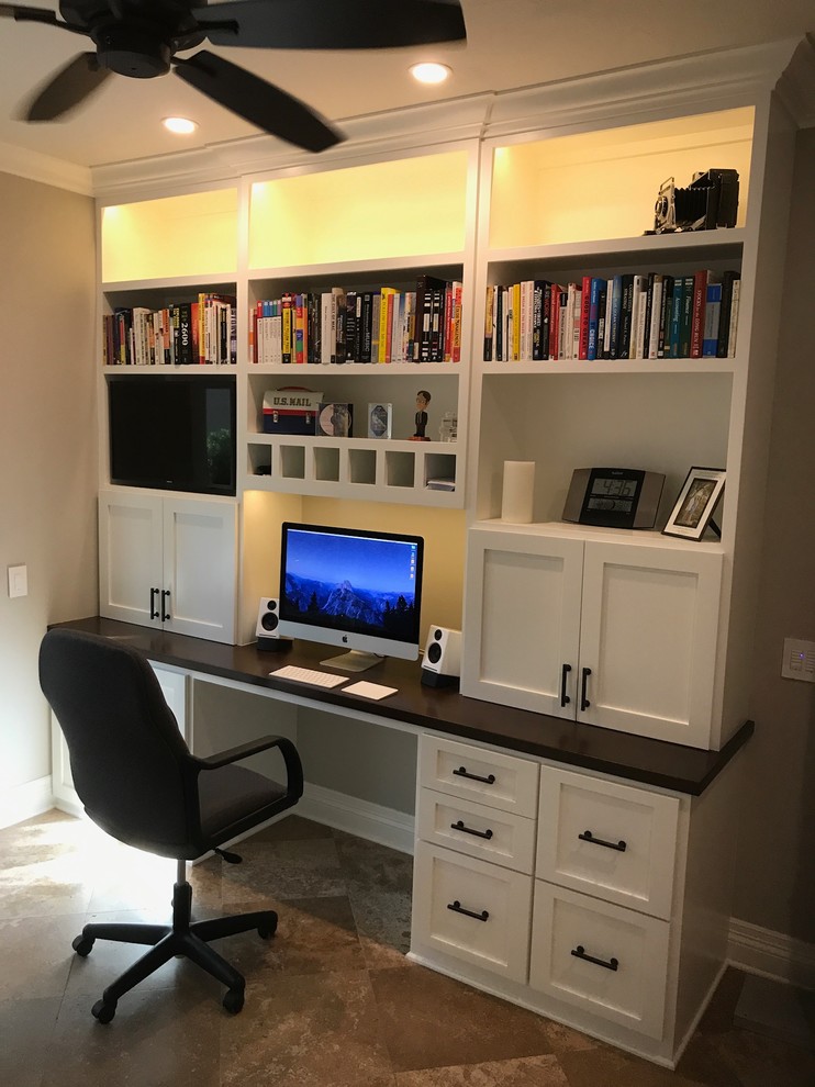 Diseño de despacho tradicional pequeño con paredes marrones, suelo de piedra caliza, escritorio empotrado y suelo marrón