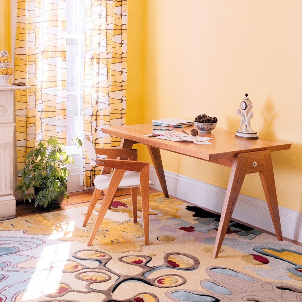 Ejemplo de despacho actual con paredes amarillas, suelo de madera en tonos medios y escritorio independiente