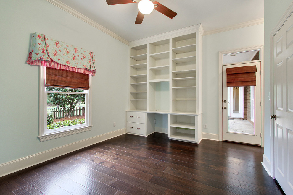 Ejemplo de despacho clásico renovado de tamaño medio sin chimenea con paredes azules, suelo de madera oscura y escritorio empotrado