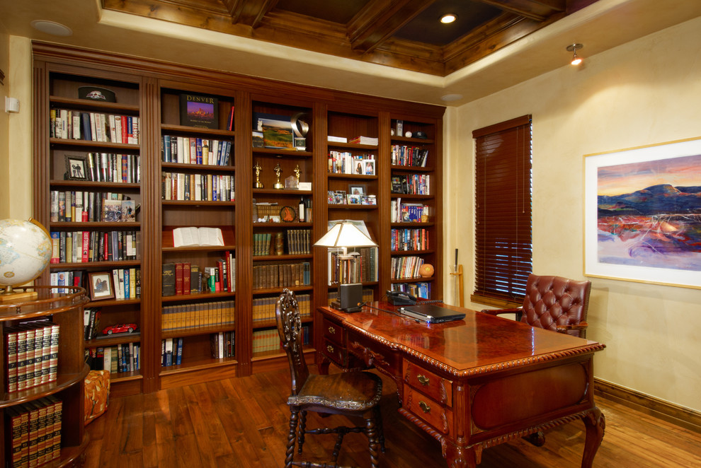 Idéer för att renovera ett stort medelhavsstil hemmabibliotek, med beige väggar, mellanmörkt trägolv och ett fristående skrivbord