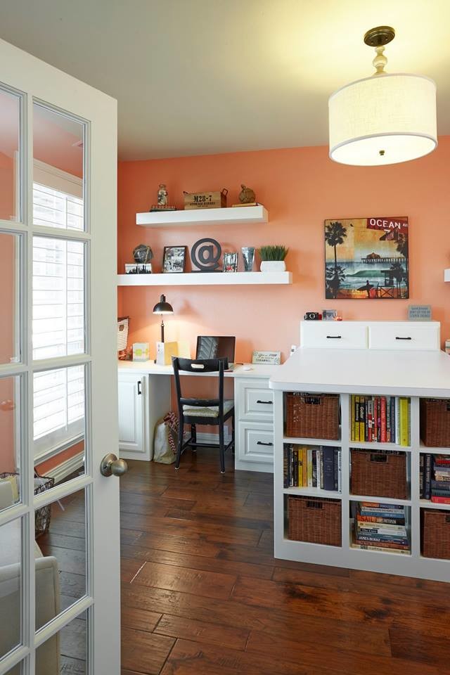 Aménagement d'un grand bureau atelier contemporain avec un mur orange, parquet foncé, un bureau intégré et un sol marron.
