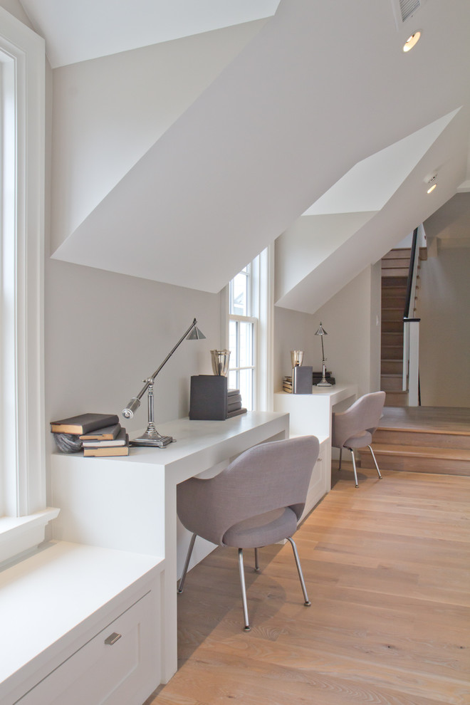 Modelo de despacho campestre de tamaño medio sin chimenea con escritorio empotrado, paredes blancas y suelo de madera clara