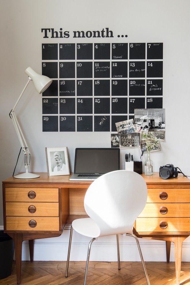 Modernes Arbeitszimmer ohne Kamin mit weißer Wandfarbe, braunem Holzboden, freistehendem Schreibtisch und braunem Boden in Sonstige