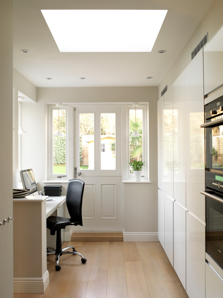 ロンドンにあるトランジショナルスタイルのおしゃれなホームオフィス・書斎 (白い壁、無垢フローリング、造り付け机、ベージュの床) の写真