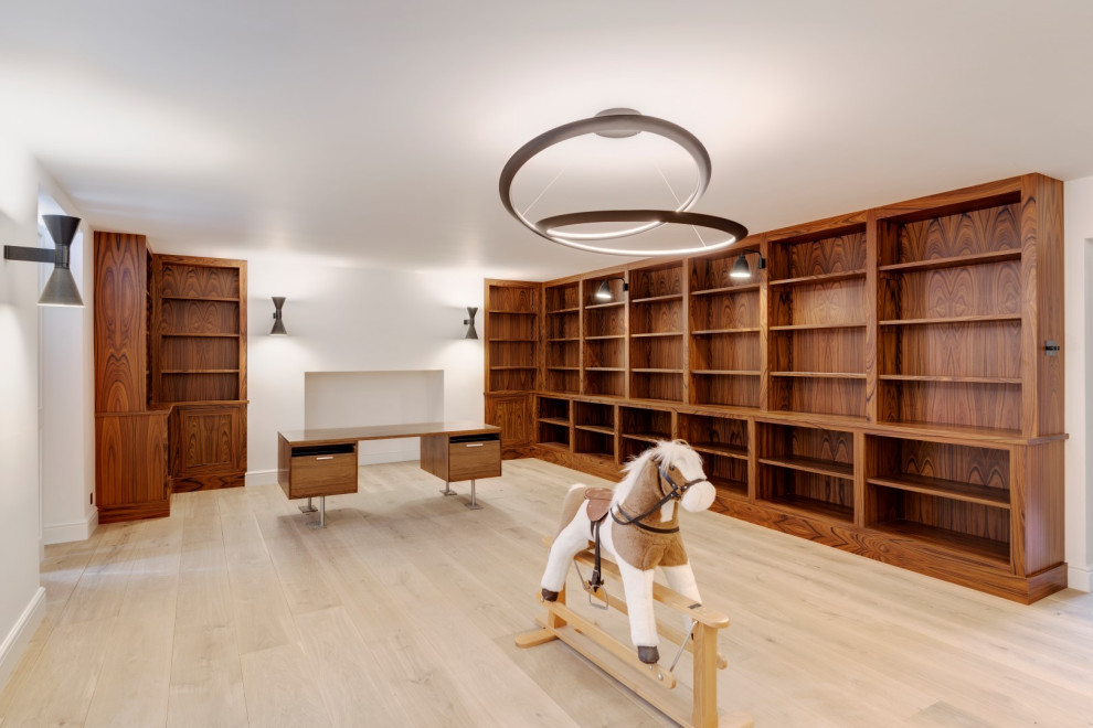 Idéer för ett stort klassiskt hemmabibliotek, med vita väggar, ljust trägolv, ett inbyggt skrivbord och beiget golv