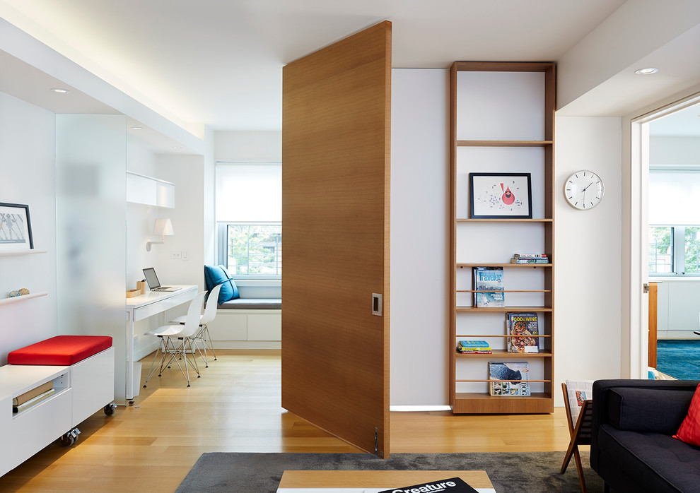 Mittelgroßes Modernes Arbeitszimmer ohne Kamin mit weißer Wandfarbe, braunem Holzboden, freistehendem Schreibtisch und Studio in New York