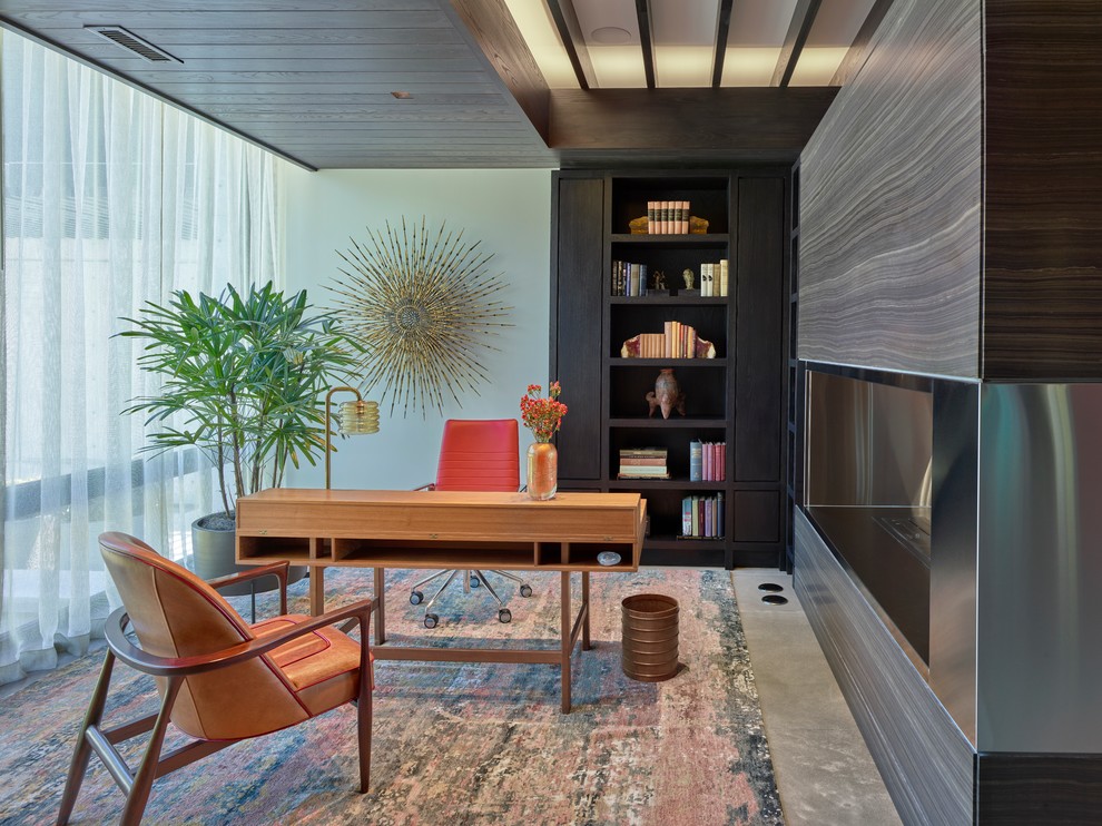 他の地域にある広いコンテンポラリースタイルのおしゃれなホームオフィス・書斎 (自立型机、グレーの床、赤い壁、コンクリートの床) の写真