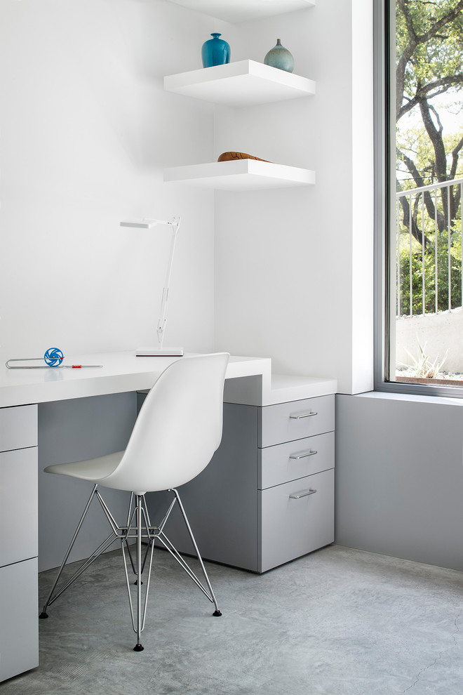 Immagine di un ufficio moderno di medie dimensioni con pareti bianche, pavimento in cemento, pavimento grigio e scrivania incassata