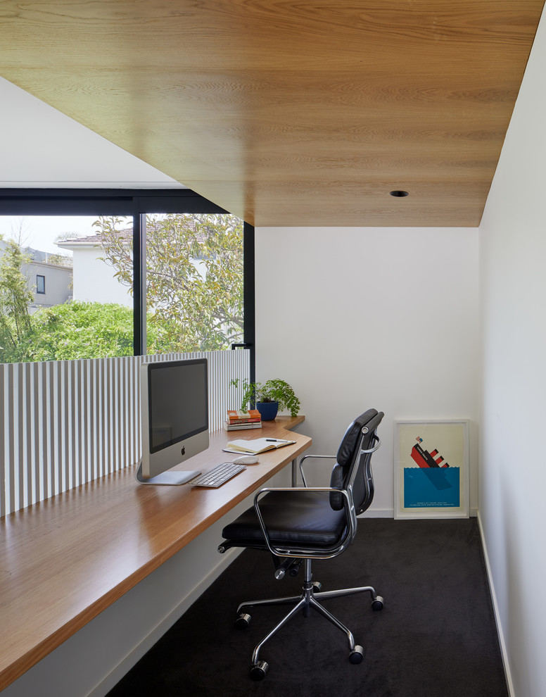Стильный дизайн: маленький кабинет в современном стиле с белыми стенами, ковровым покрытием, встроенным рабочим столом и черным полом для на участке и в саду - последний тренд