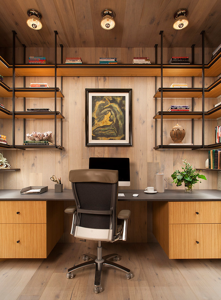 Immagine di uno studio design con libreria, parquet chiaro e scrivania incassata
