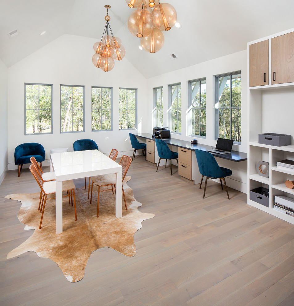 Modelo de despacho contemporáneo grande con paredes blancas, suelo de madera en tonos medios, escritorio empotrado y suelo gris