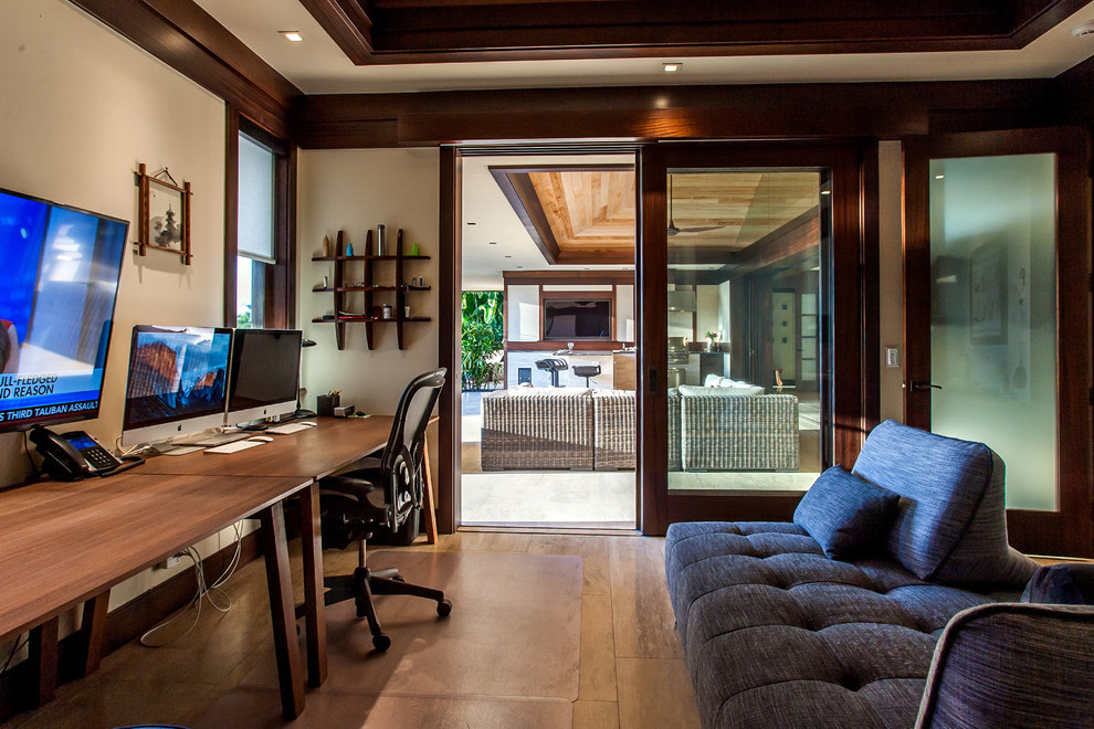 Imagen de despacho tropical con paredes beige, suelo de madera en tonos medios y escritorio independiente
