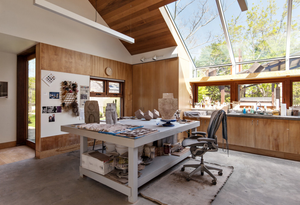 Idee per un atelier contemporaneo con pareti marroni, pavimento in cemento, scrivania autoportante, pavimento grigio, soffitto a volta e pareti in legno