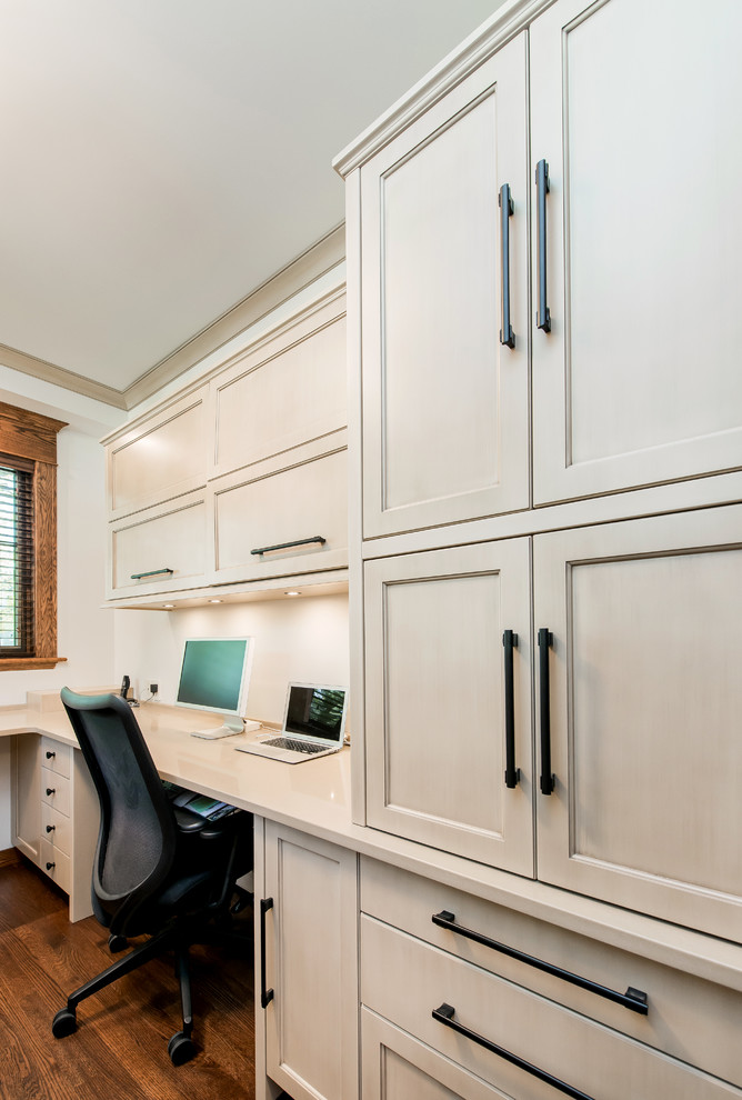 Großes Klassisches Arbeitszimmer ohne Kamin mit Arbeitsplatz, weißer Wandfarbe, braunem Holzboden und Einbau-Schreibtisch in Calgary