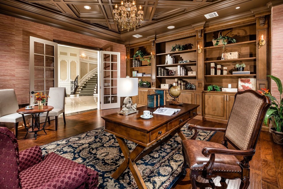 Klassisches Arbeitszimmer mit Arbeitsplatz, brauner Wandfarbe, braunem Holzboden und freistehendem Schreibtisch in Los Angeles