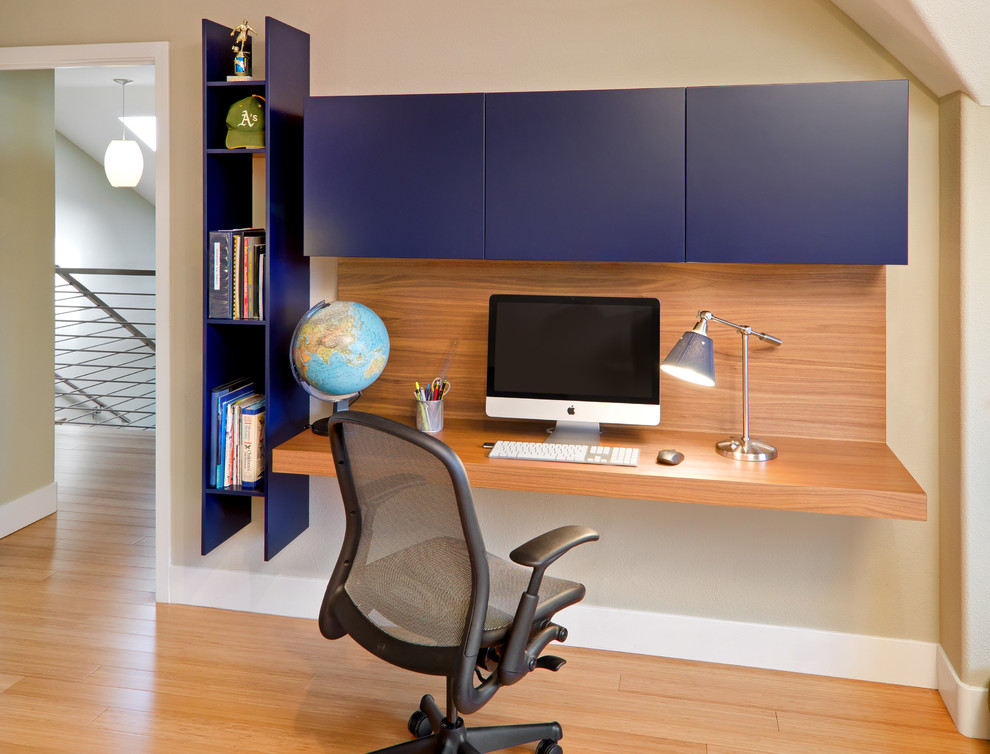 This is an example of a contemporary home office in San Francisco with beige walls, bamboo flooring and a built-in desk.