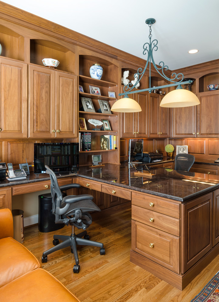 На фото: домашняя библиотека в классическом стиле с коричневыми стенами, паркетным полом среднего тона и встроенным рабочим столом с