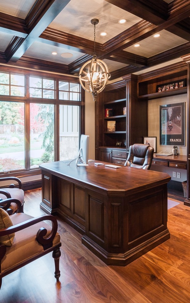 Ejemplo de despacho tradicional de tamaño medio sin chimenea con suelo de madera en tonos medios, escritorio independiente y paredes beige