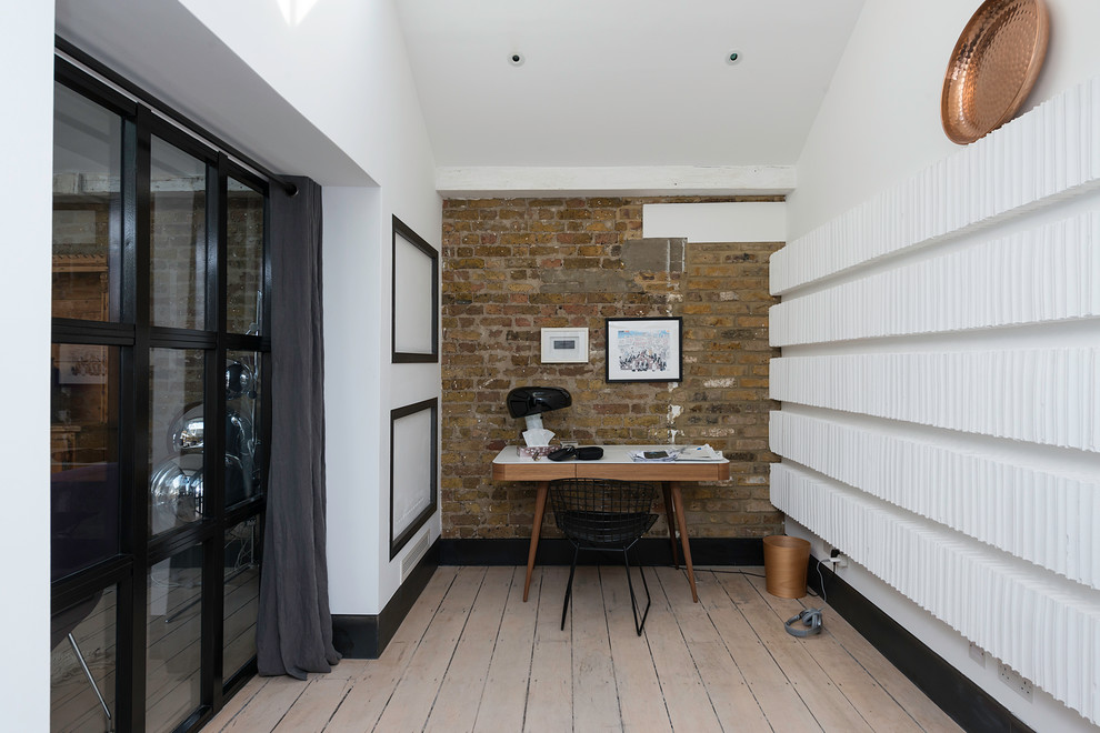 Medium sized study in London with light hardwood flooring and a freestanding desk.