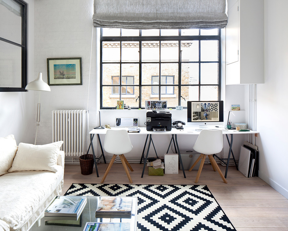 Mittelgroßes Skandinavisches Arbeitszimmer mit weißer Wandfarbe, hellem Holzboden, braunem Boden und freistehendem Schreibtisch in London