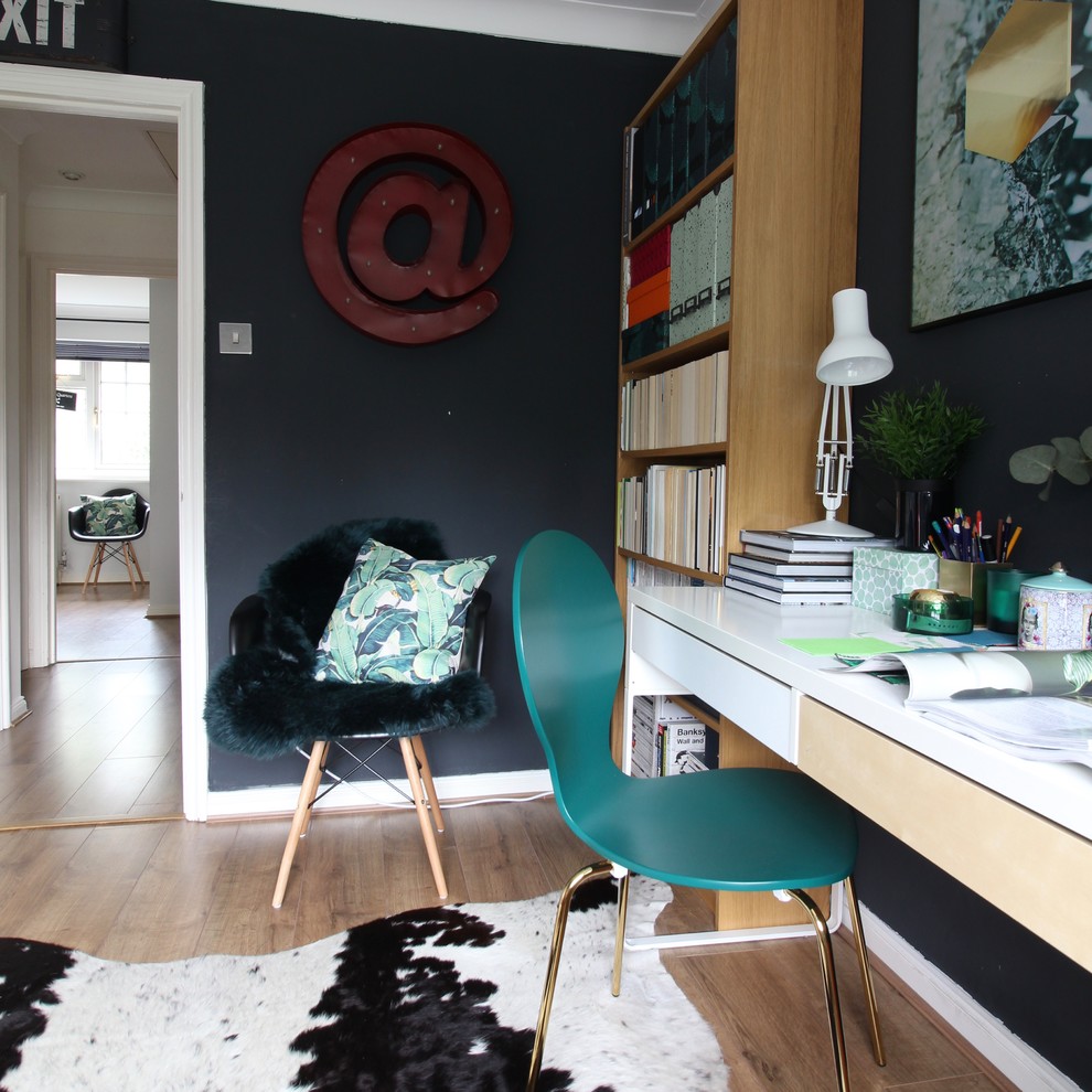 Esempio di un piccolo ufficio eclettico con pareti nere, pavimento in laminato, scrivania autoportante e pavimento marrone