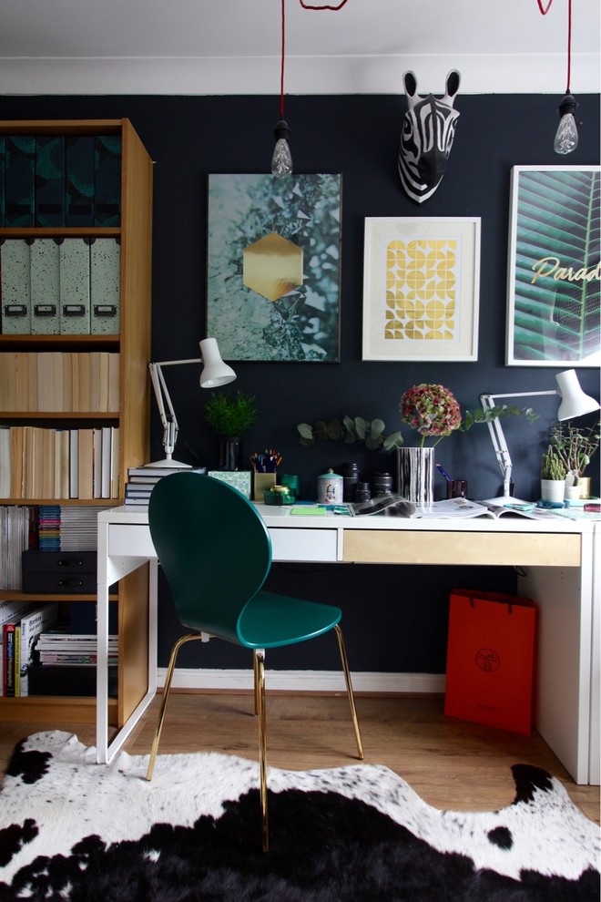 Inspiration för ett litet eklektiskt hemmabibliotek, med svarta väggar, laminatgolv, ett fristående skrivbord och brunt golv