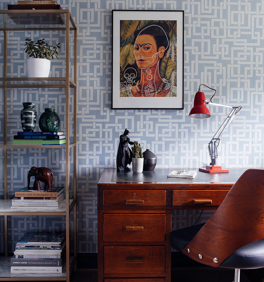 Foto på ett litet eklektiskt hemmabibliotek, med blå väggar, laminatgolv, ett fristående skrivbord och brunt golv