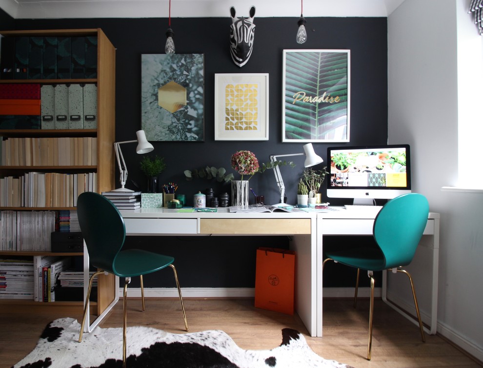 Immagine di un ufficio bohémian con pareti nere, pavimento in laminato, scrivania autoportante e pavimento marrone