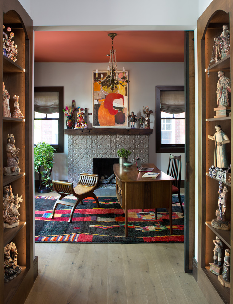Stilmix Arbeitszimmer mit weißer Wandfarbe, hellem Holzboden, Kamin, gefliester Kaminumrandung, freistehendem Schreibtisch und beigem Boden in Denver