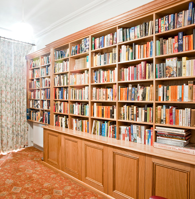 Esempio di un grande studio tradizionale con libreria, pareti bianche, moquette, camino classico e cornice del camino in legno