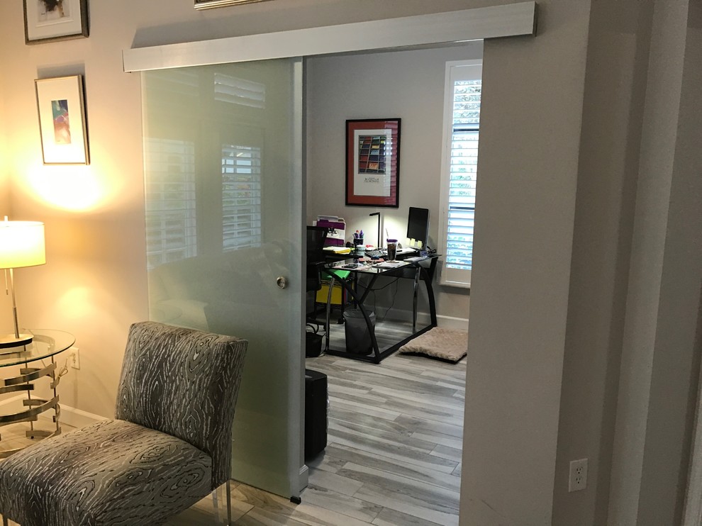 Ejemplo de despacho actual de tamaño medio sin chimenea con paredes grises, suelo de madera clara y escritorio independiente