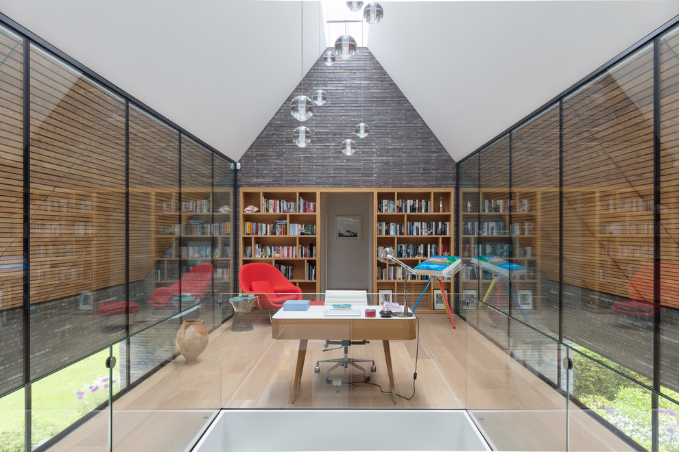 Inspiration för moderna hemmabibliotek, med ljust trägolv, ett fristående skrivbord och beiget golv