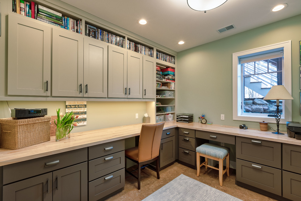 Ejemplo de sala de manualidades de estilo americano de tamaño medio sin chimenea con paredes verdes, suelo de corcho, escritorio empotrado y suelo beige