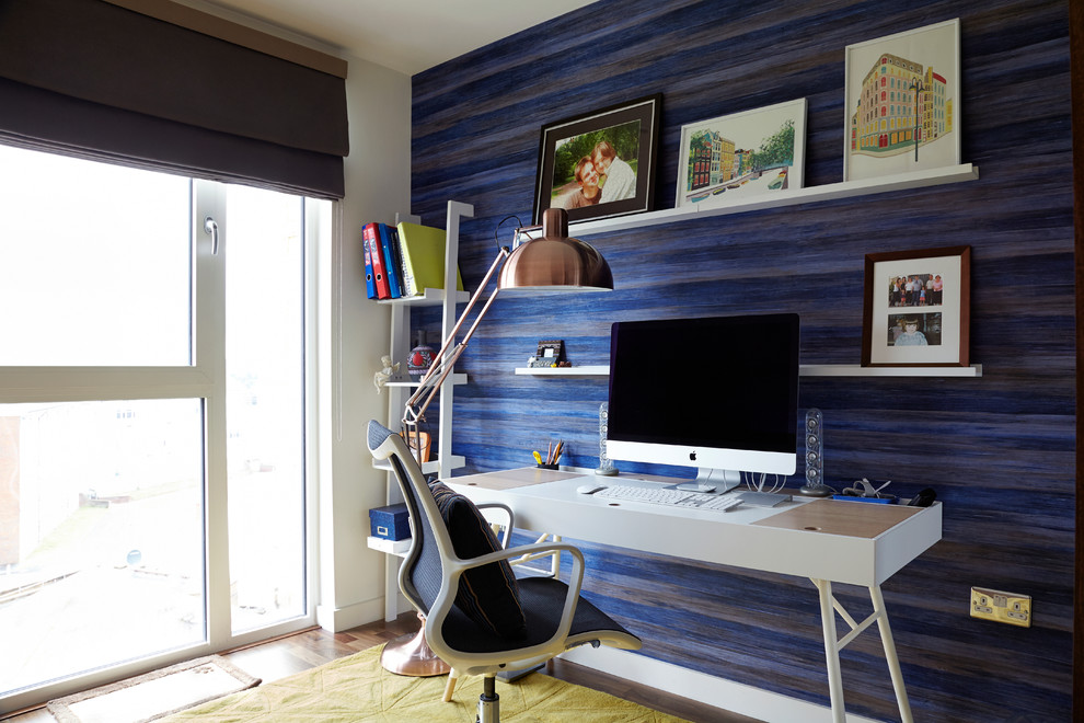 На фото: маленькое рабочее место в стиле модернизм с синими стенами, темным паркетным полом и отдельно стоящим рабочим столом без камина для на участке и в саду