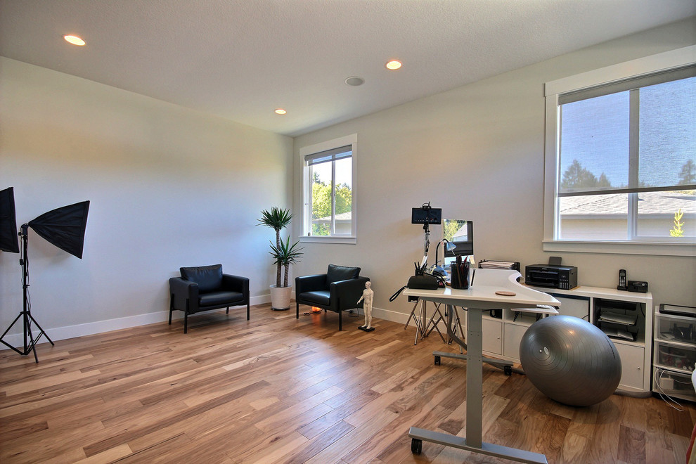 Idée de décoration pour un très grand bureau minimaliste de type studio avec un mur beige, un sol en bois brun, aucune cheminée, un bureau indépendant et un sol marron.