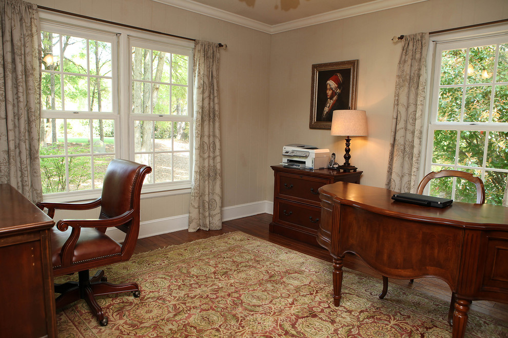 Landhausstil Arbeitszimmer mit beiger Wandfarbe, braunem Holzboden und freistehendem Schreibtisch in Charlotte