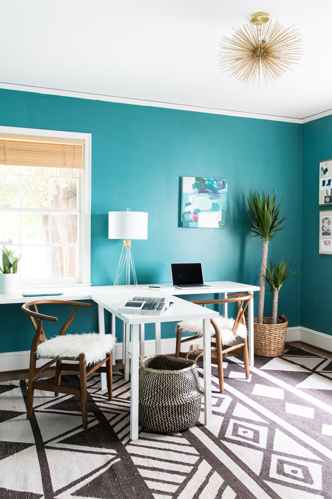 Inredning av ett modernt mellanstort hemmastudio, med blå väggar, ett fristående skrivbord, mörkt trägolv och brunt golv