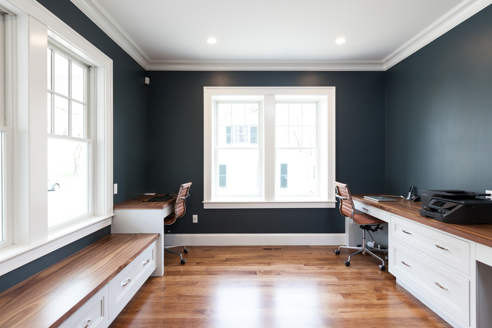 This is an example of a medium sized traditional study in Boston with blue walls, dark hardwood flooring, a built-in desk and brown floors.