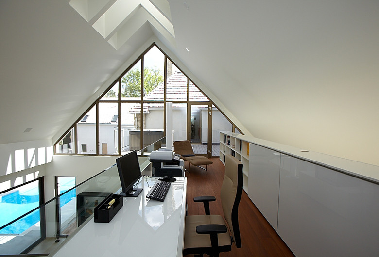 Bild på ett mellanstort funkis hemmastudio, med vita väggar, mellanmörkt trägolv och ett fristående skrivbord