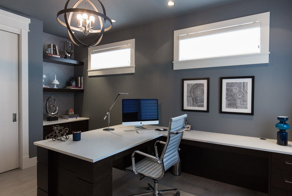 Cette image montre un grand bureau design avec un mur gris, parquet clair, un bureau intégré et un sol gris.