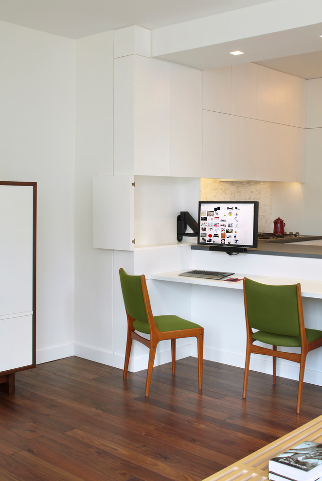 Стильный дизайн: маленькое рабочее место в стиле модернизм с белыми стенами, паркетным полом среднего тона и встроенным рабочим столом для на участке и в саду - последний тренд