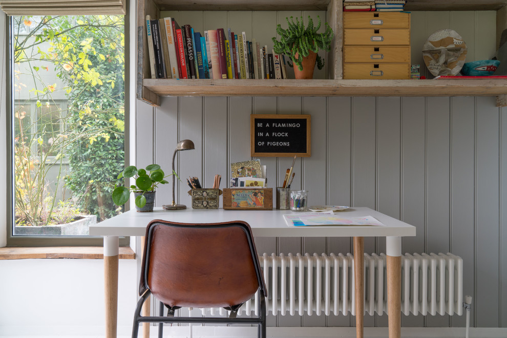 Bild på ett eklektiskt arbetsrum, med ett bibliotek, grå väggar och ett fristående skrivbord