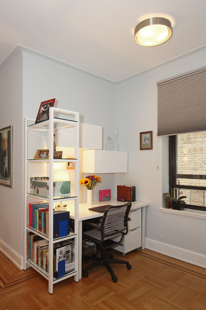 Foto på ett litet funkis arbetsrum, med blå väggar, mellanmörkt trägolv och ett fristående skrivbord