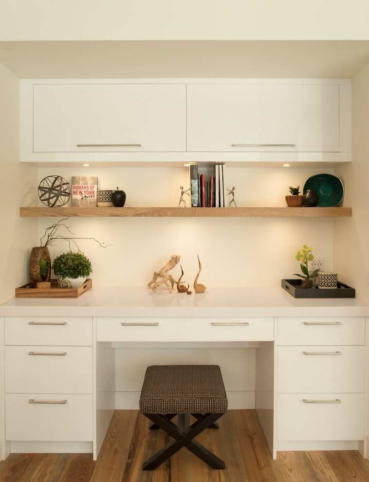 Exemple d'un bureau tendance de taille moyenne avec un mur blanc, un sol en bois brun, aucune cheminée, un bureau intégré et un sol marron.
