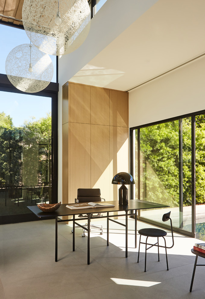 Идея дизайна: кабинет в стиле модернизм с белыми стенами, бетонным полом, отдельно стоящим рабочим столом и серым полом