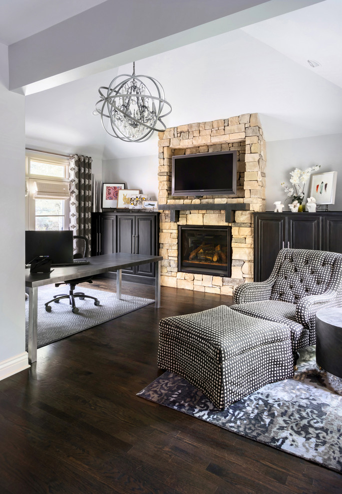 This is an example of a medium sized traditional home office in Omaha with grey walls, dark hardwood flooring, a standard fireplace, a stone fireplace surround, a freestanding desk and brown floors.